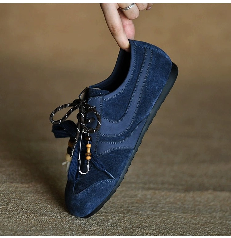 Navy blue suede sneaker with stacked amber and white bead lace charms and precise stitched upper panels