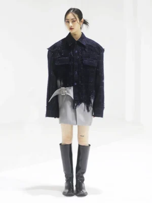 Full-body view of a women’s navy cropped tweed fringe jacket styled with a grey mini skirt and black knee-high boots in a modern streetwear outfit