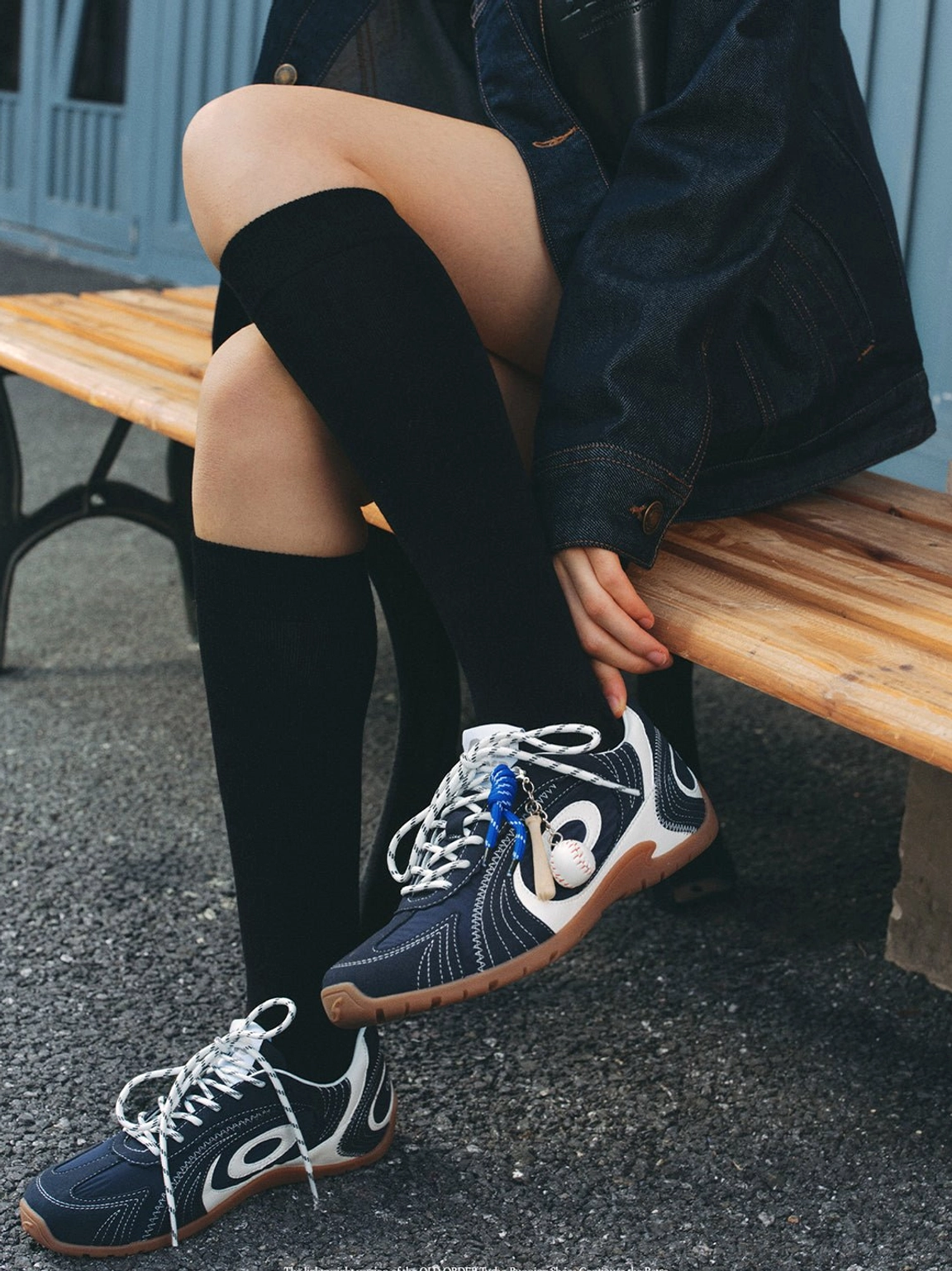 Navy low-profile retro trainers styled with black knee-high socks and dark denim in an outdoor streetwear look