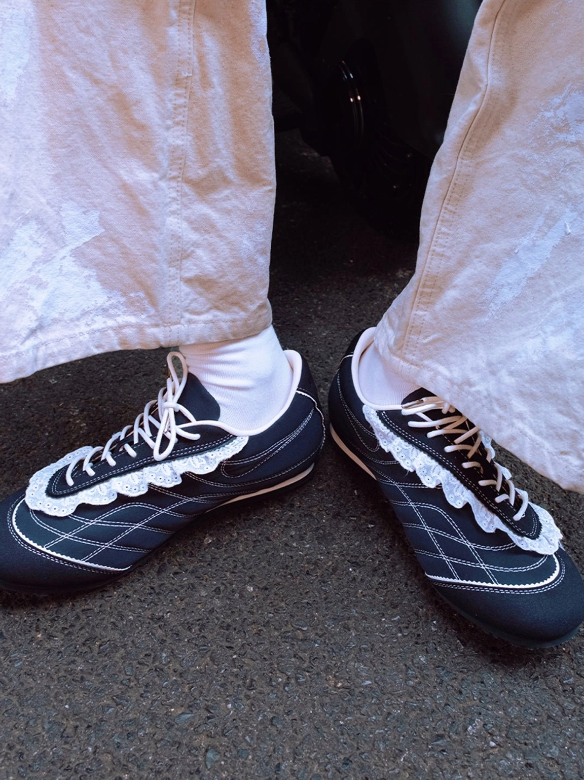Navy low-profile retro trainers worn with white socks and off-white pants, featuring grid contrast stitching