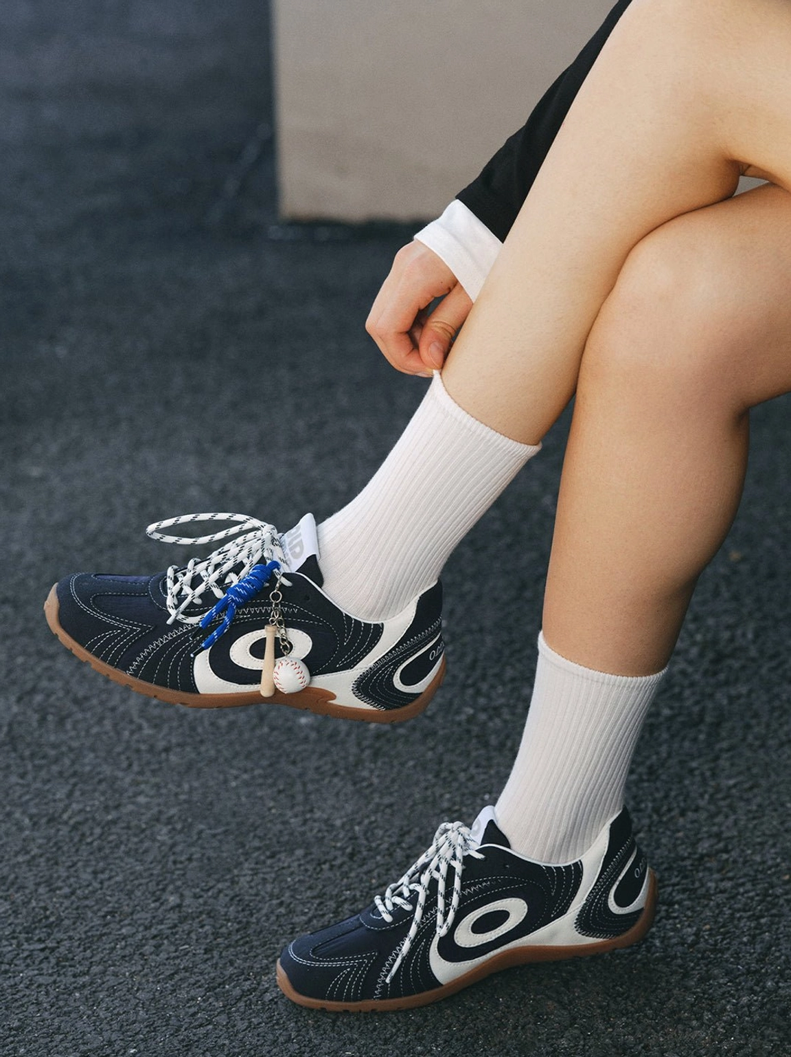 Navy low-profile sneakers with blue decorative details worn with white crew socks in a casual streetwear outfit