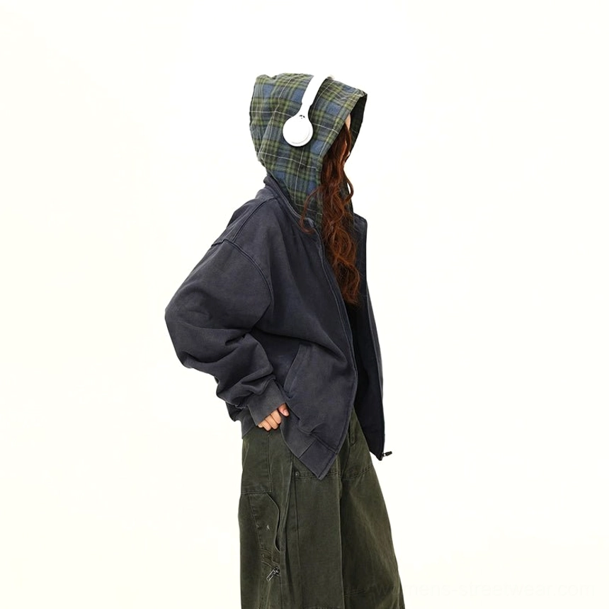 Three-quarter styling view of the navy oversized plaid-lined hooded zip jacket worn with headphones and casual streetwear