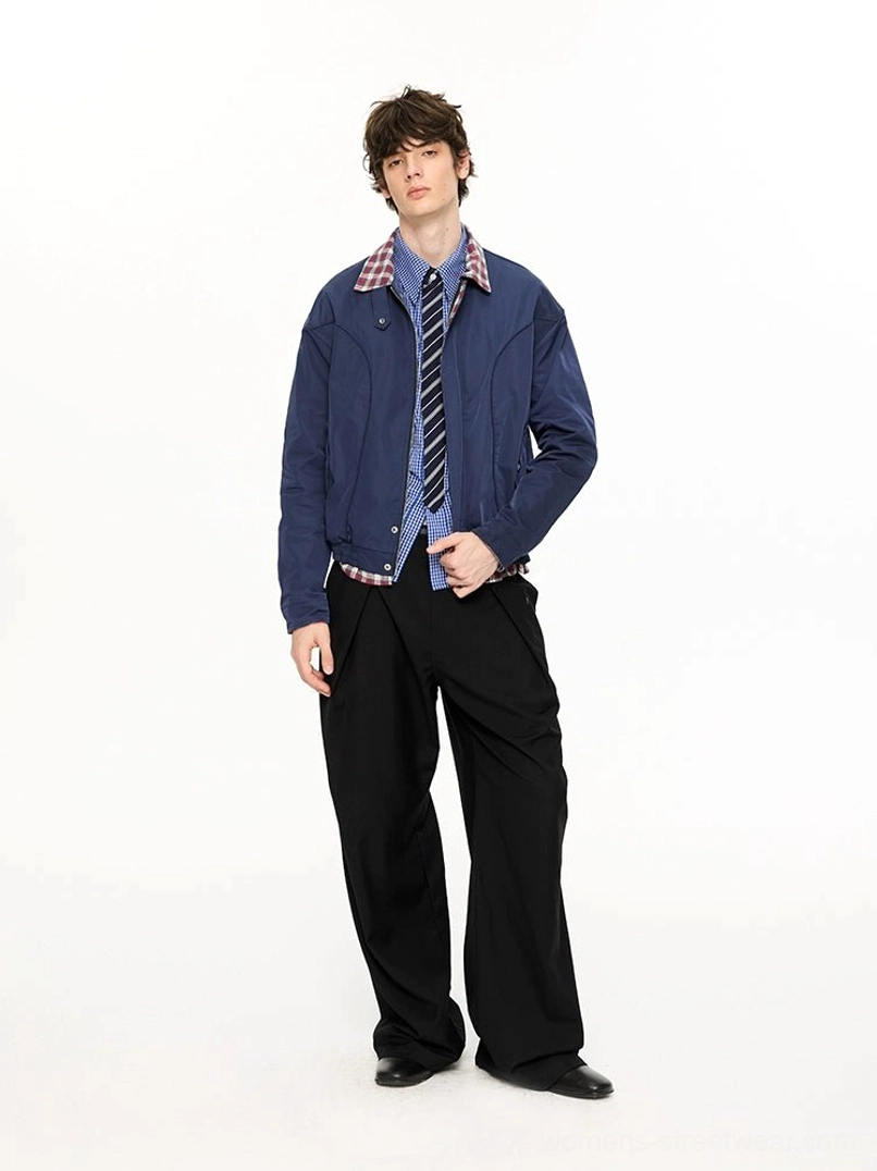 Full body side-front view of navy blue plaid-lined Harrington jacket styled with checked shirt tie and wide-leg trousers