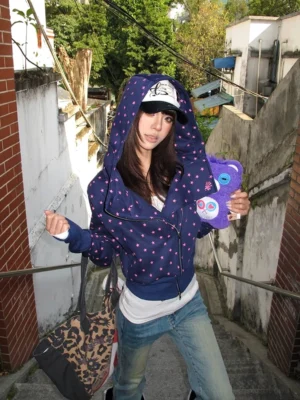 Dark navy polka dot cropped zip-up hoodie worn in a three-quarter front view with sculptural hood and asymmetrical zipper in an outdoor streetwear setting