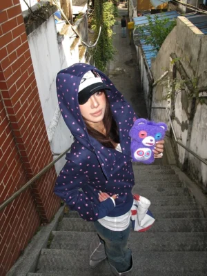 Dark navy polka dot cropped hoodie shown from the side with hood up, long slim sleeves, and modern Korean streetwear silhouette on outdoor stairs