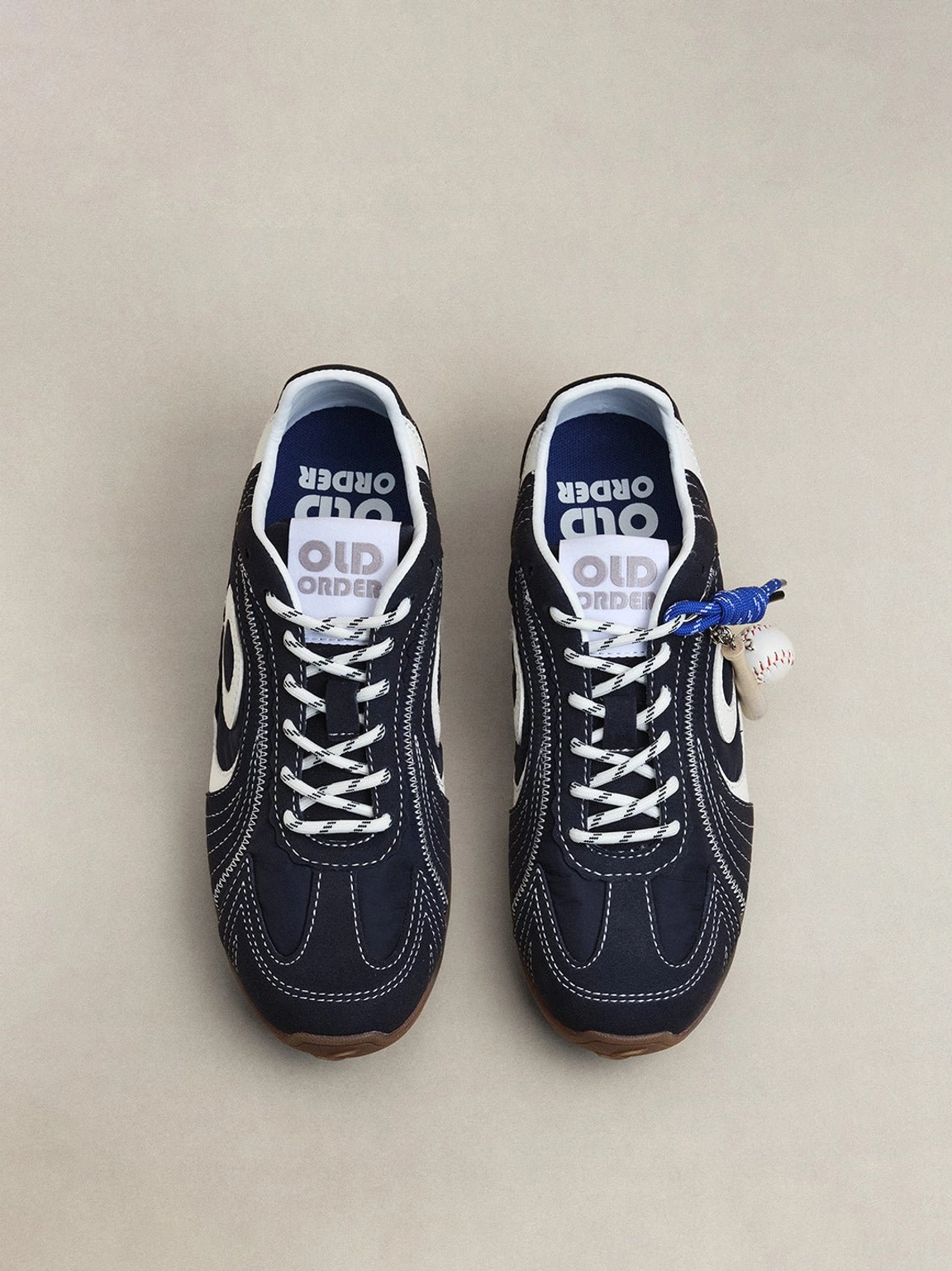 Navy retro low-profile sneakers featuring flowing white swirl panels, blue laces, and gum rubber soles
