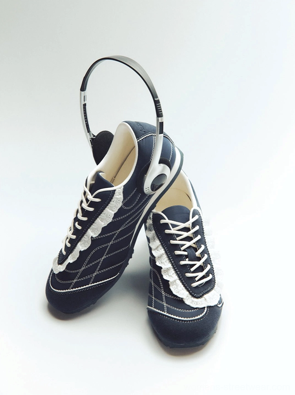 Pair of navy ruffled lace streetwear trainers with white contrast stitching and vintage headphones studio styling