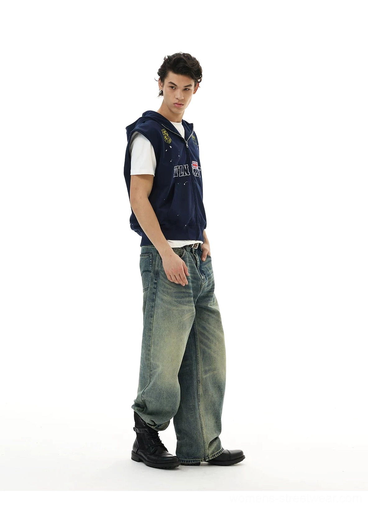 Side full-body view of navy sleeveless hooded streetwear vest worn over a white basic T-shirt and faded jeans