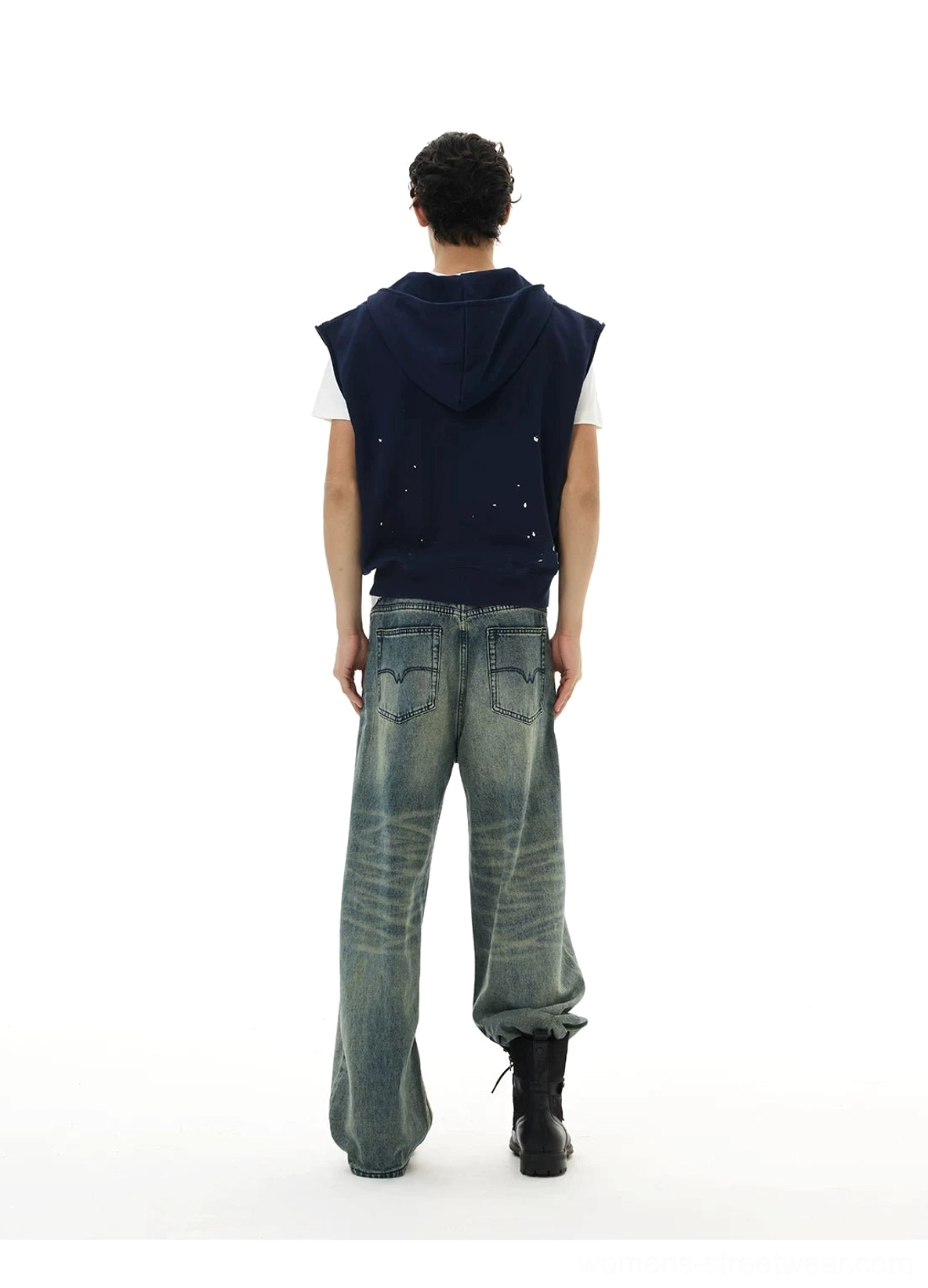 Back view of navy sleeveless zip hoodie vest with paint-splatter accents styled with denim and work boots