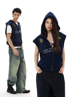 Navy sleeveless zip hoodie vest shown on two models with crest graphics, flag details, denim styling, and leather boots