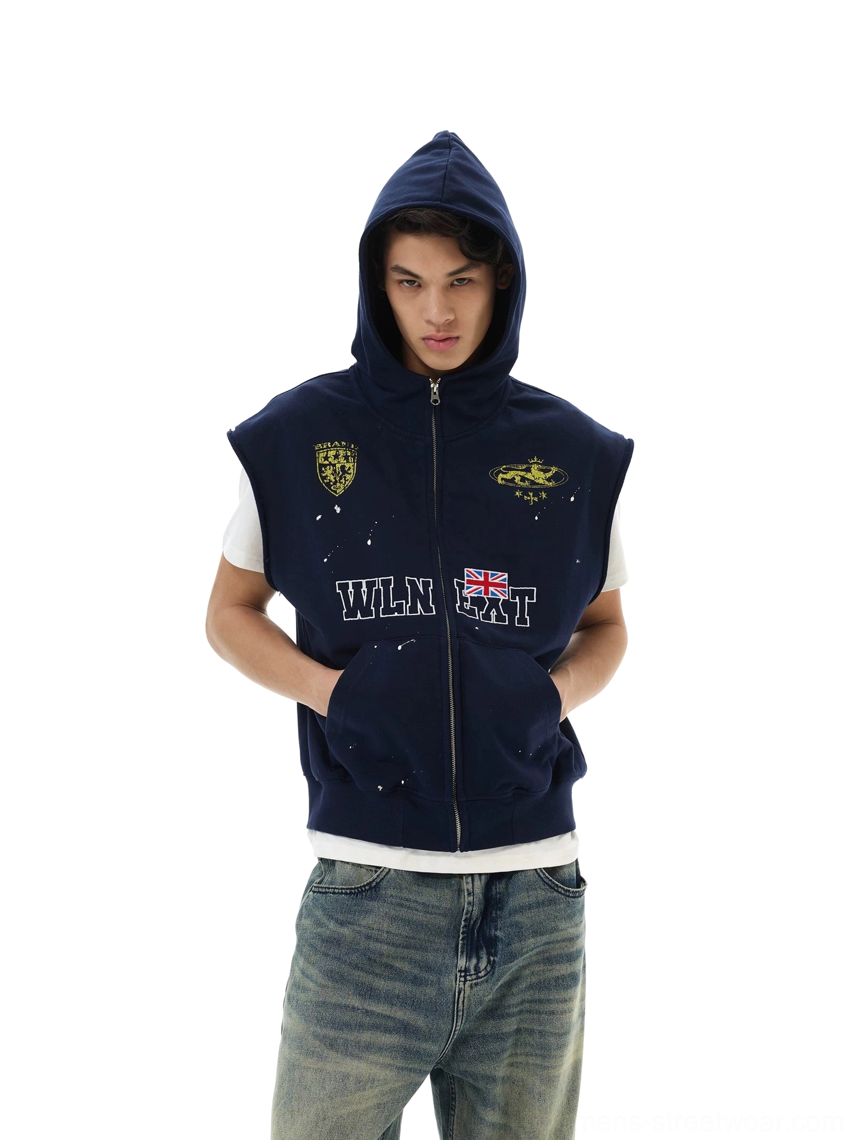 Front view of male model wearing navy sleeveless zip hoodie vest with hood, printed lettering, and badge graphics