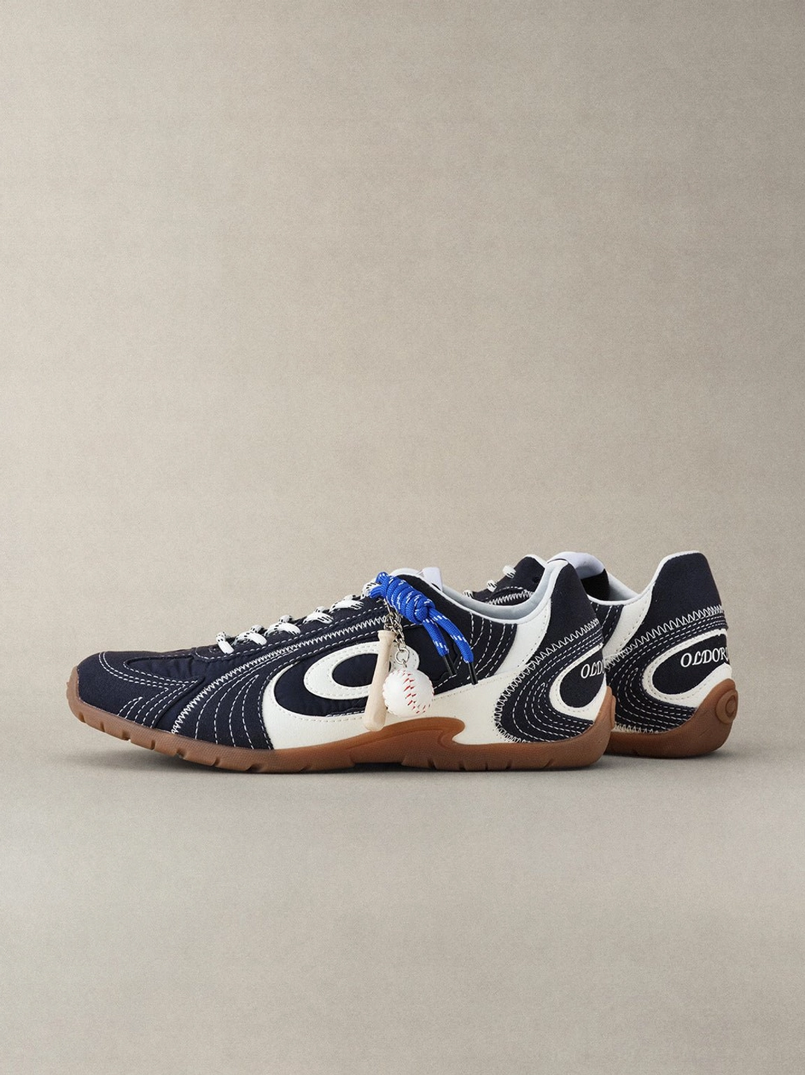Navy swirl-panel low-profile streetwear trainers with cream overlays, cobalt accents, and gum sole product detail