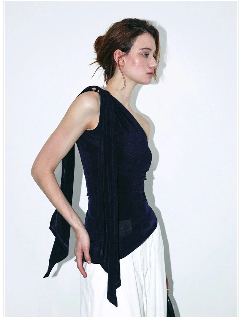 Side profile of a navy velvet asymmetric top with long flowing sash, one-shoulder neckline, and sleek fitted shape