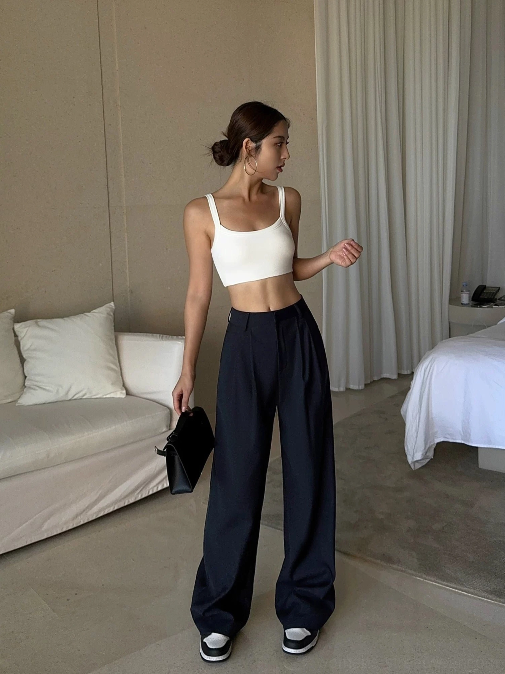 Deep navy wide-leg tailored trousers shown from the side with front pleats and fluid suiting fabric