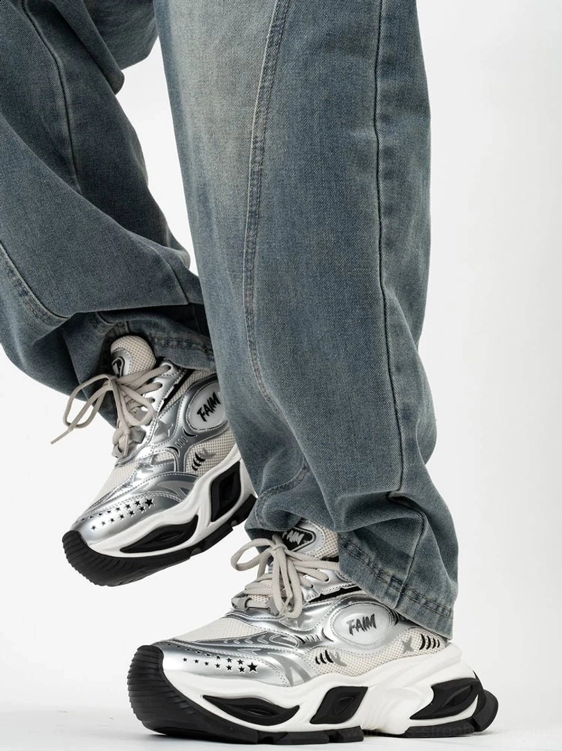 Low angle view of silver metallic high-lift fashion sneakers with black and white layered outsole, perforated toe, and futuristic chunky runner shape