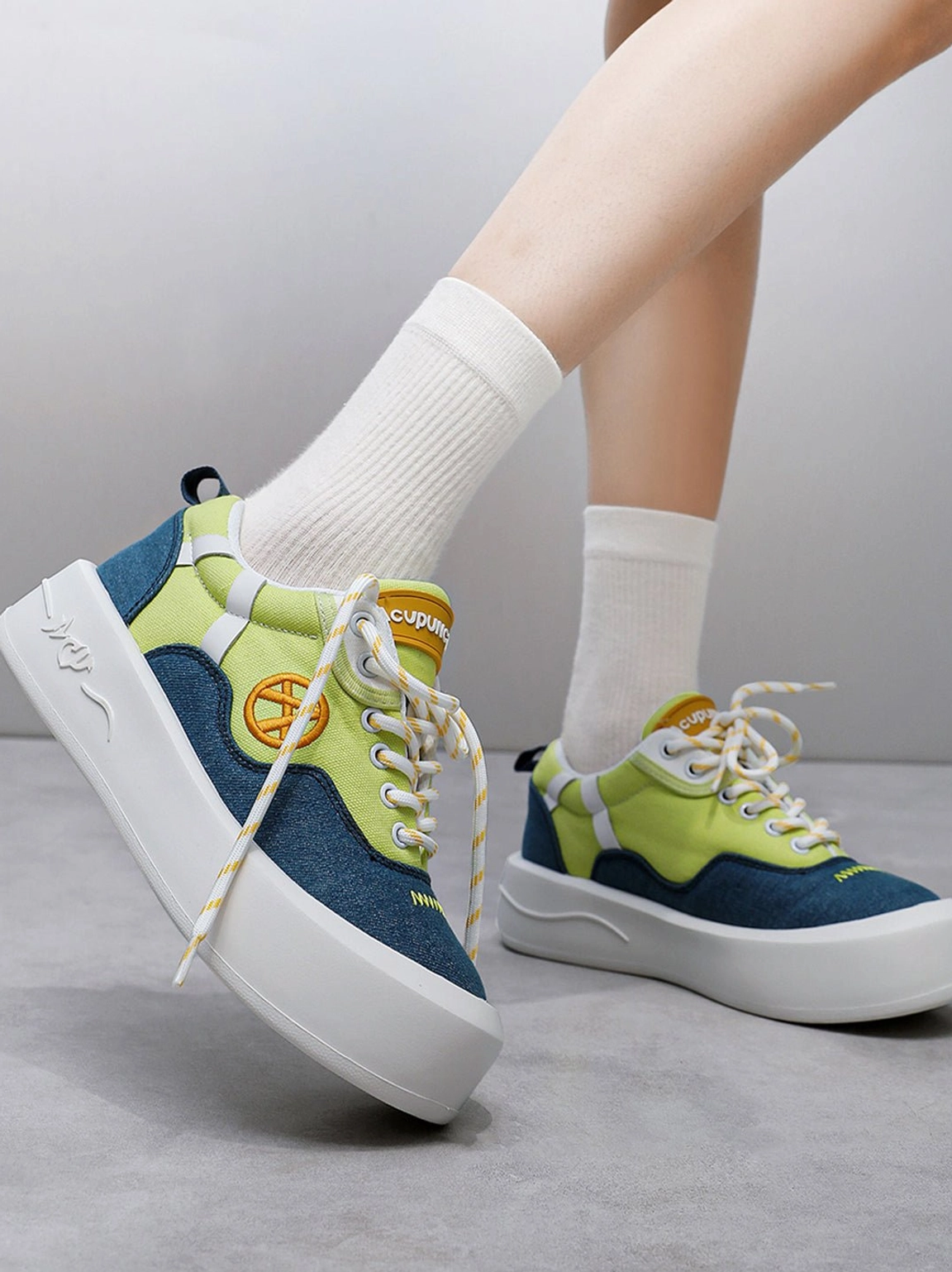 Rear side view of neon canvas platform sneakers worn with white crew socks showing wavy sole and heel pull tab