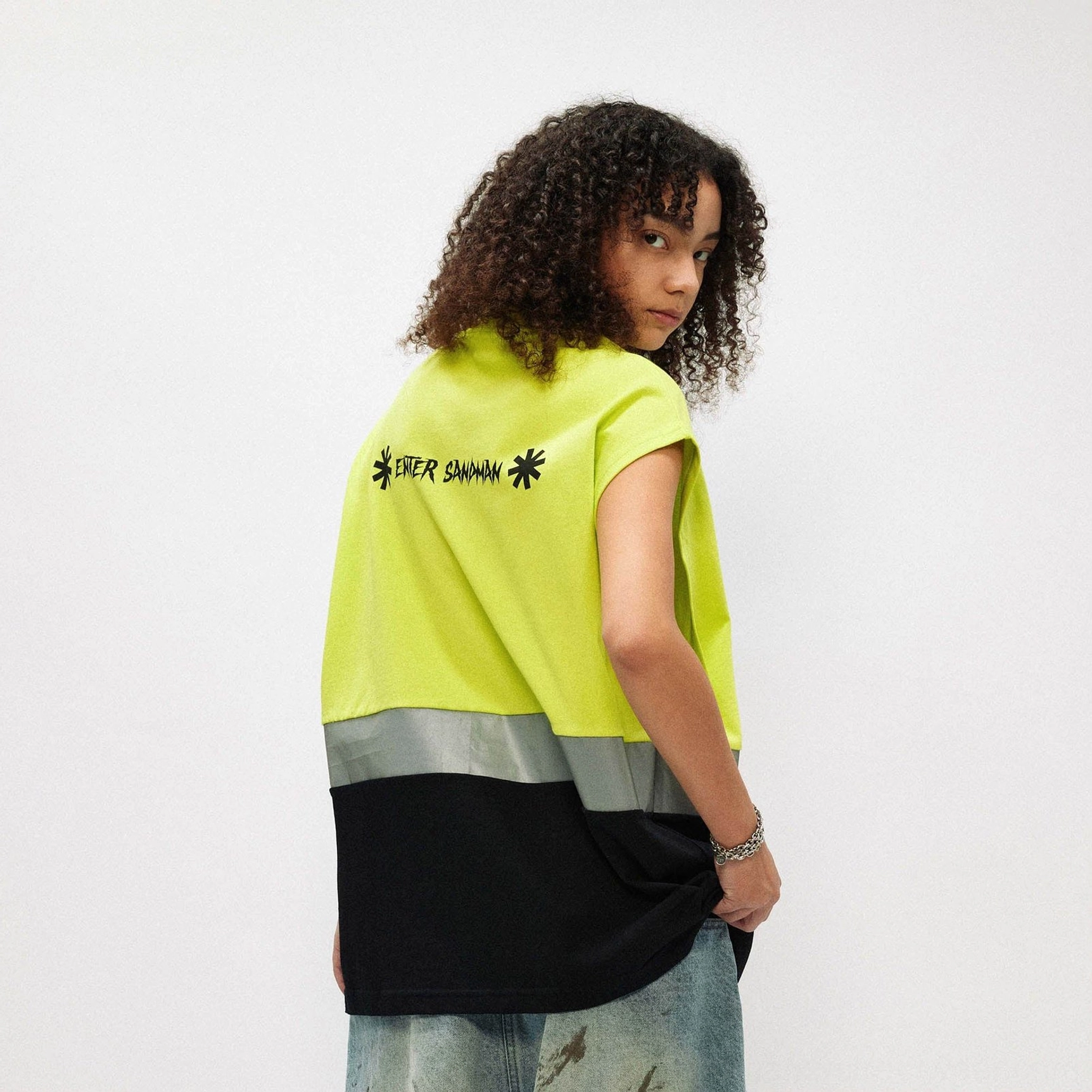 Back view of fluorescent lime and black oversized gothic tank top with reflective stripe and enter sandman text
