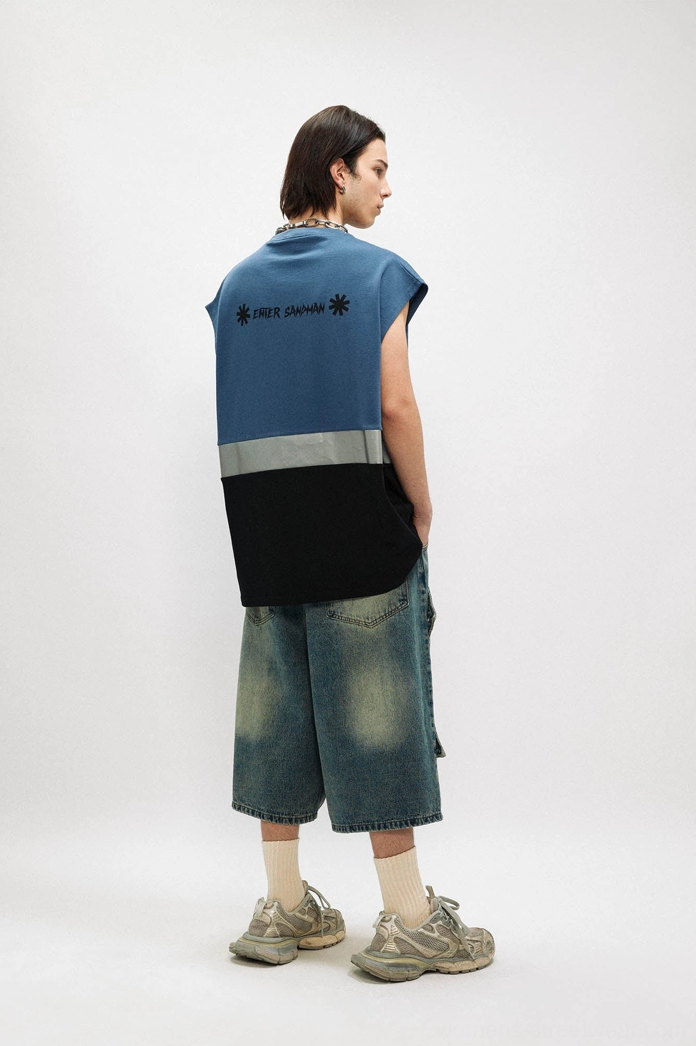 Male model wearing dusty blue oversized gothic tank top with denim shorts, vintage sneakers, and enter sandman back print