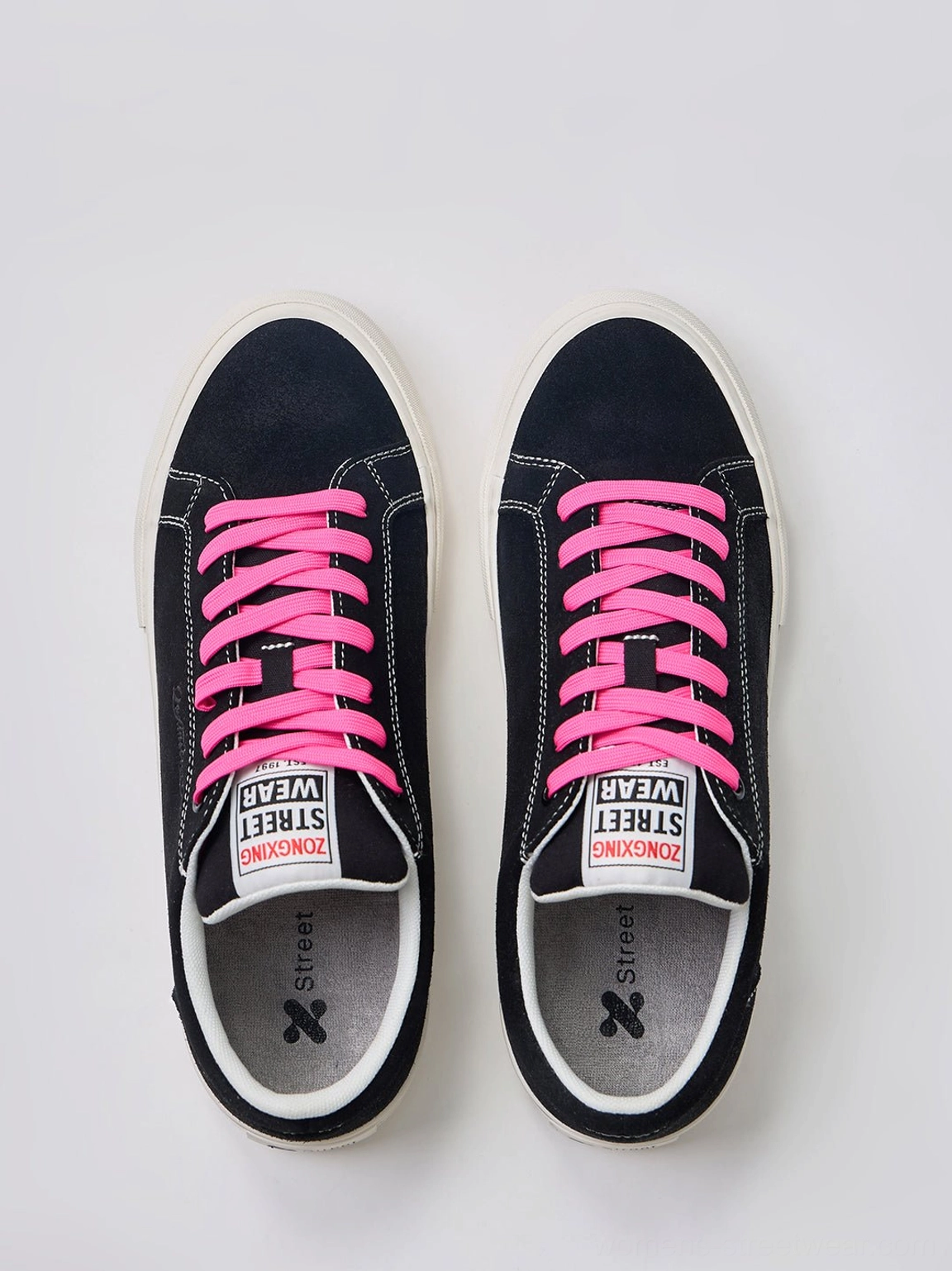 Overhead view of black suede platform canvas sneakers featuring neon pink laces, contrast white trim, and graphic insoles