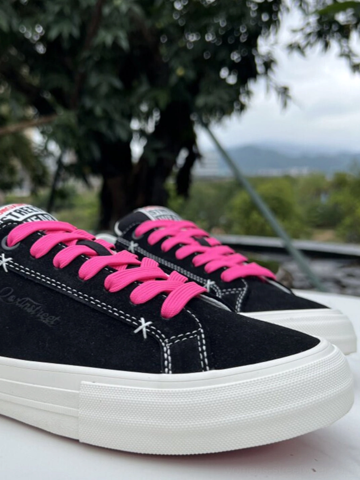 Three-quarter side view of black suede platform canvas sneakers with bright neon laces, white platform outsole, and urban casual design