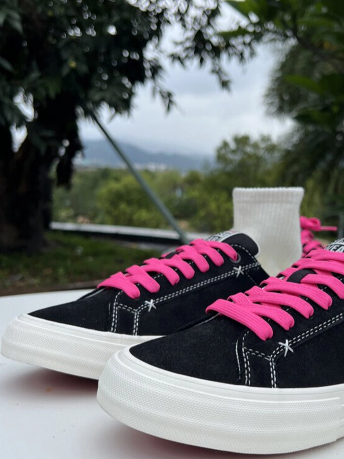Black suede neon lace platform canvas sneakers styled with white crew socks in an outdoor streetwear setting