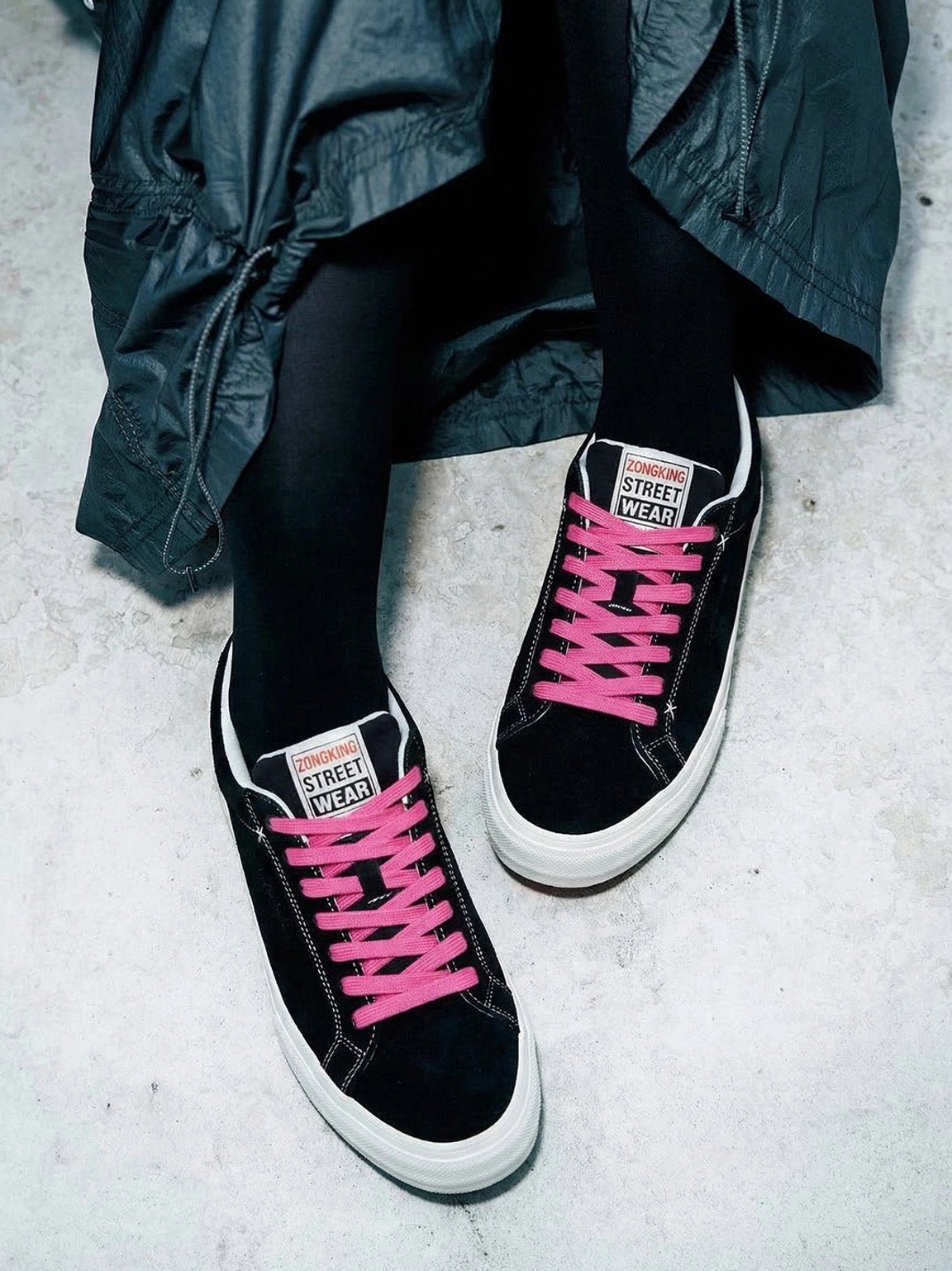 Worn black suede platform canvas sneakers with vivid neon laces, dark socks, and trench coat styling inspired by Korean street fashion