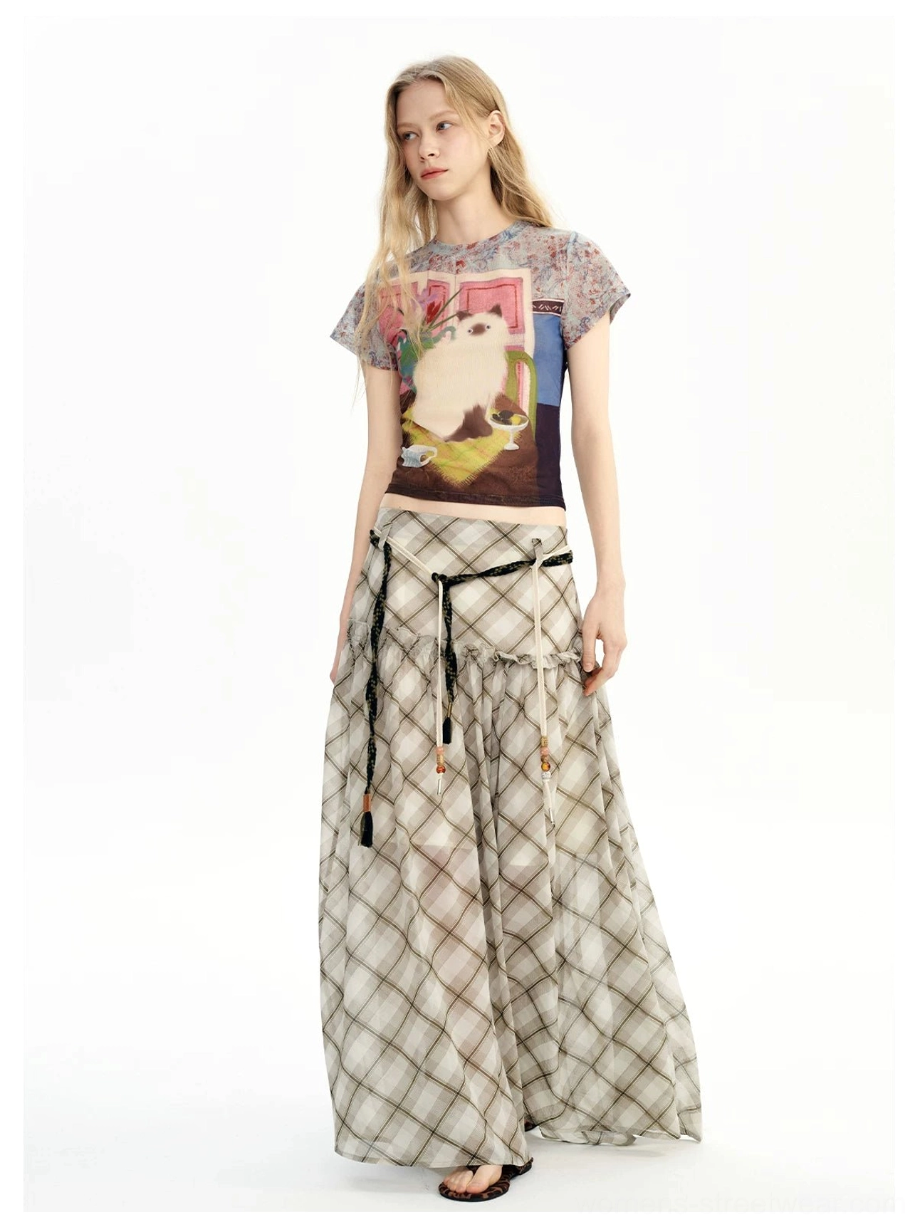 Front view of a neutral argyle plaid chiffon maxi skirt styled with a fitted cropped graphic top