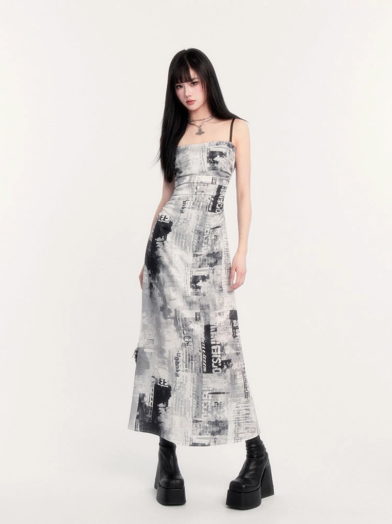 Side front view of fitted newspaper graphic slip maxi dress featuring square neckline and monochrome editorial print
