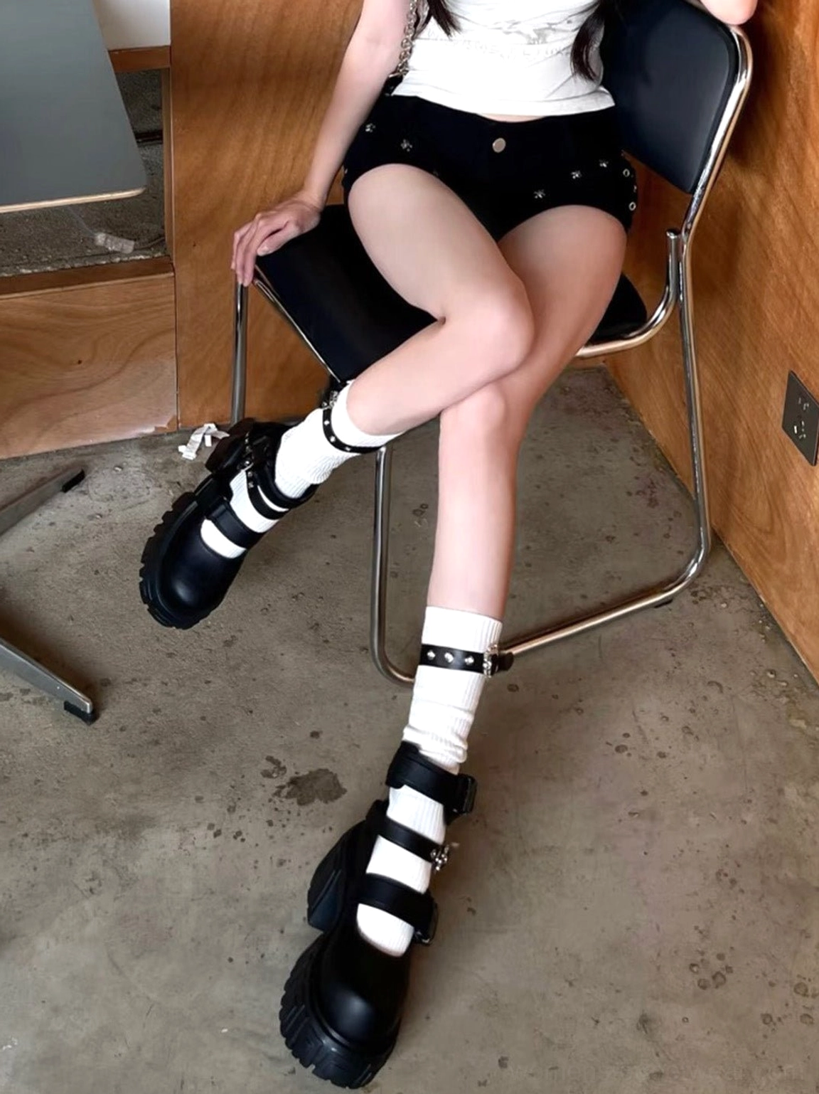 Worn black buckled platform boots with ribbed white socks and studded black shorts, showcasing alternative Korean streetwear styling