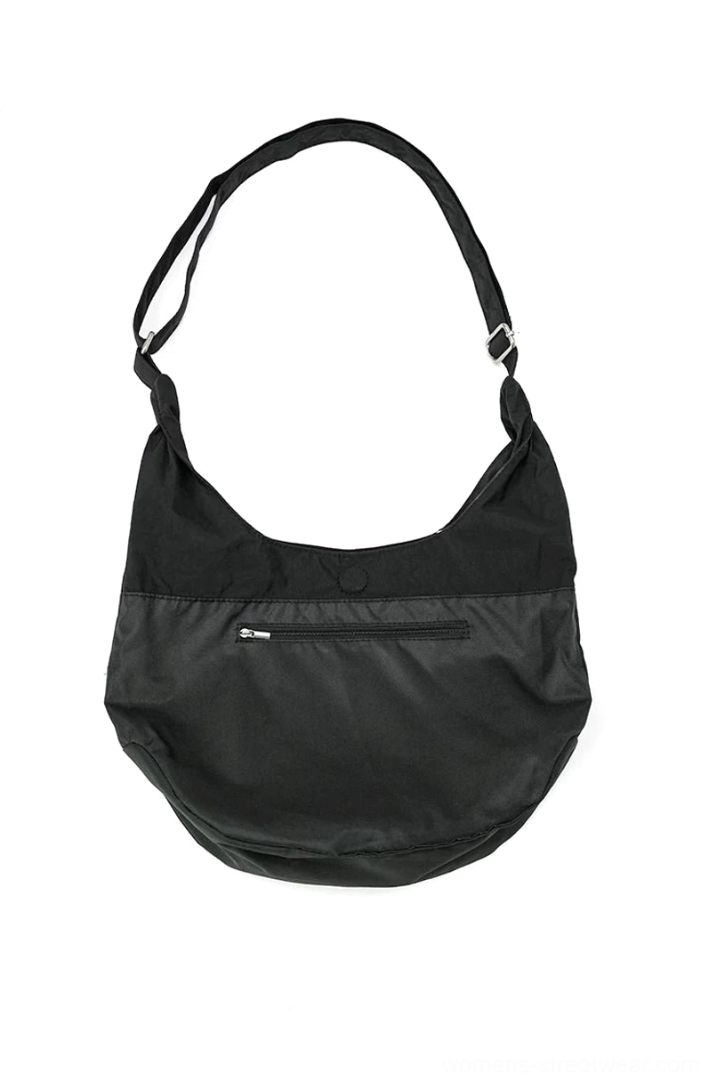 Minimalist black nylon utility sling hobo bag with curved crescent silhouette and hidden front zipper pocket