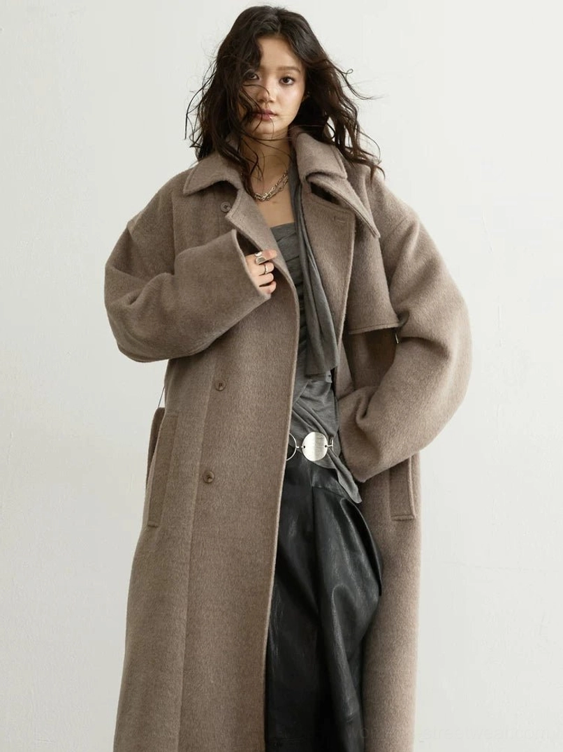 Close-up of oatmeal oversized wool blend belted trench coat with soft heathered texture and relaxed sleeves