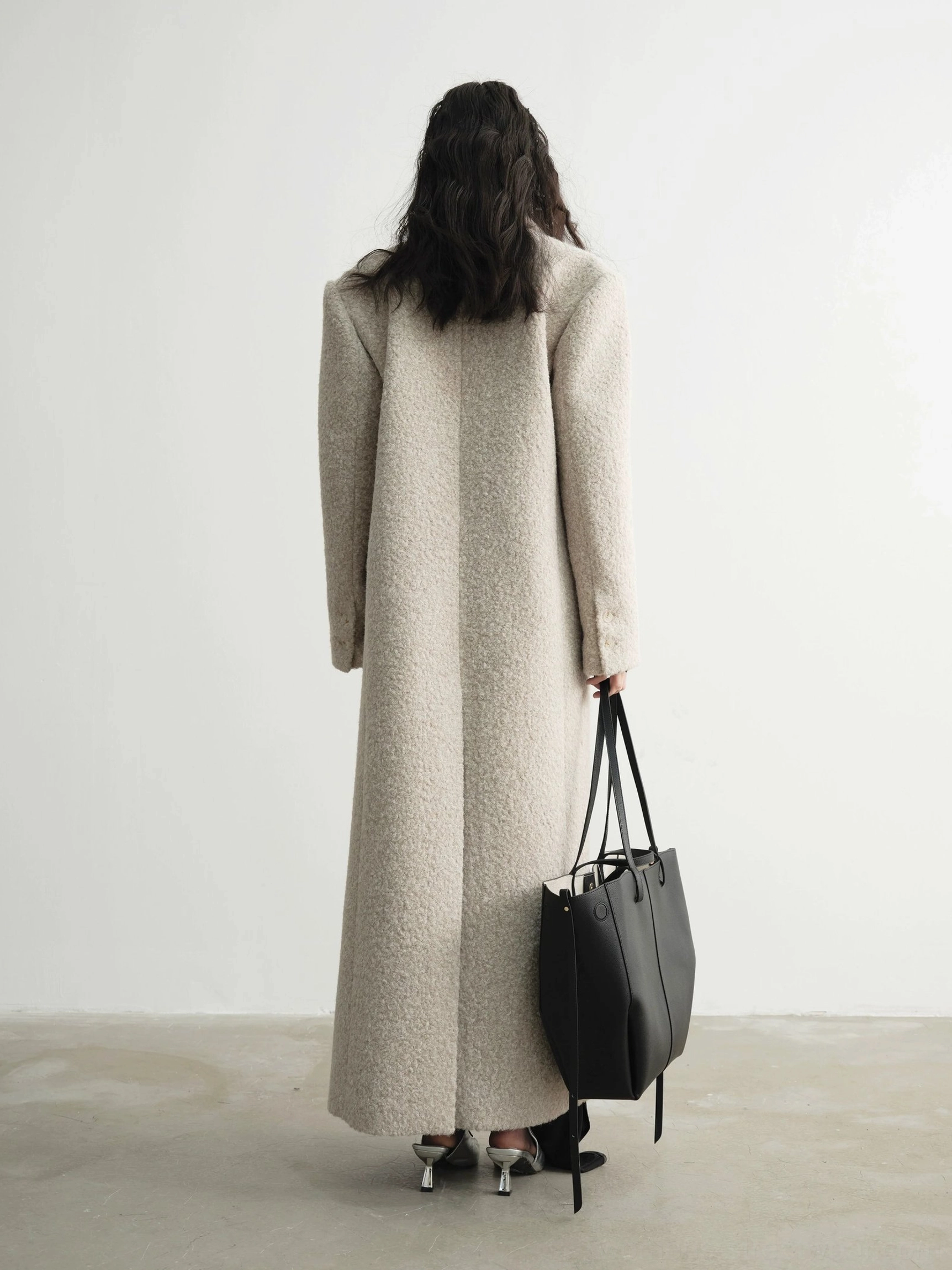 Back view of an oatmeal oversized wool maxi coat with clean minimalist construction and dramatic floor-length cut