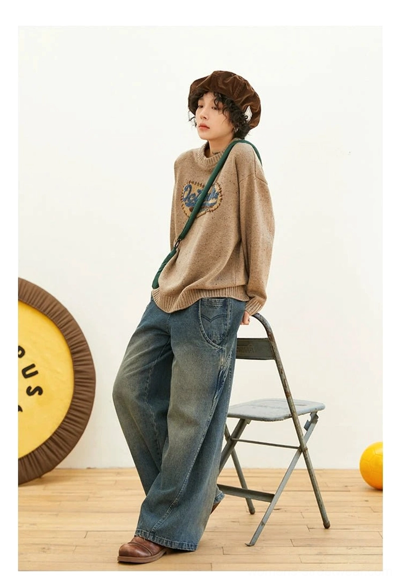 Female model wearing a relaxed oatmeal knit sweater with embroidered chest patch, wide-leg jeans, beret, and loafers in a vintage streetwear outfit