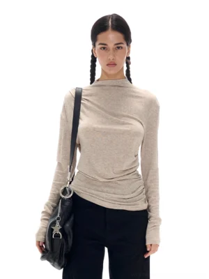Oatmeal ruched mock neck Tencel wool knit long sleeve top styled with black wide-leg trousers in front three-quarter view