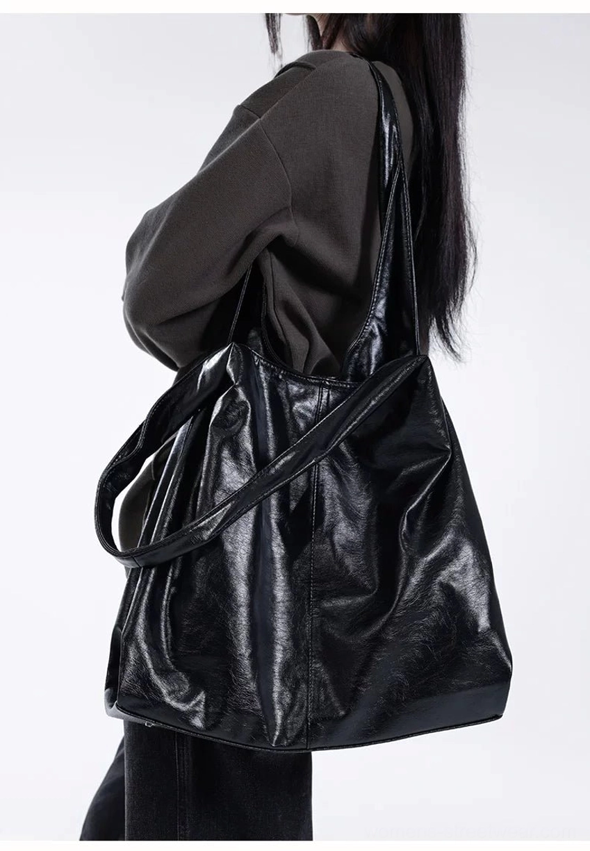 Black slouchy hobo shoulder tote with glossy textured finish worn with monochrome casual streetwear