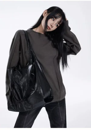 Obsidian glossy black slouch hobo tote bag worn on shoulder with dark gray streetwear outfit front view