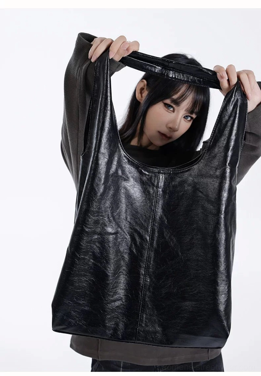 Close-up of black glossy crinkled faux leather hobo tote bag with wide opening and large capacity