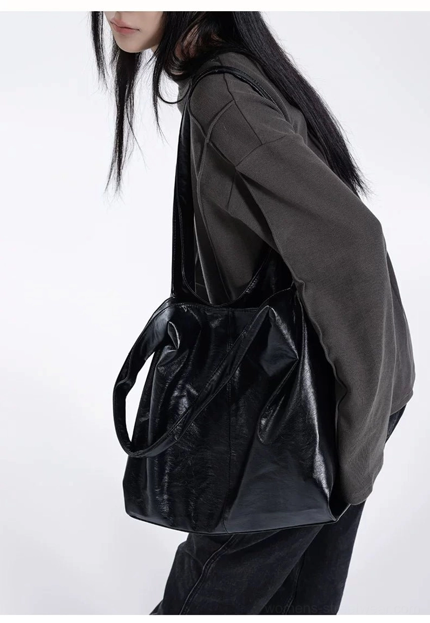 Back side view of black glossy slouch hobo tote bag with wide shoulder strap and streamlined silhouette