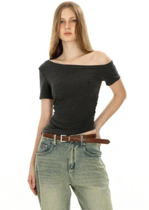 Off-shoulder dark grey minimalist tee with boat neckline and embroidered logo worn with vintage washed jeans and brown leather belt front view streetwear styling