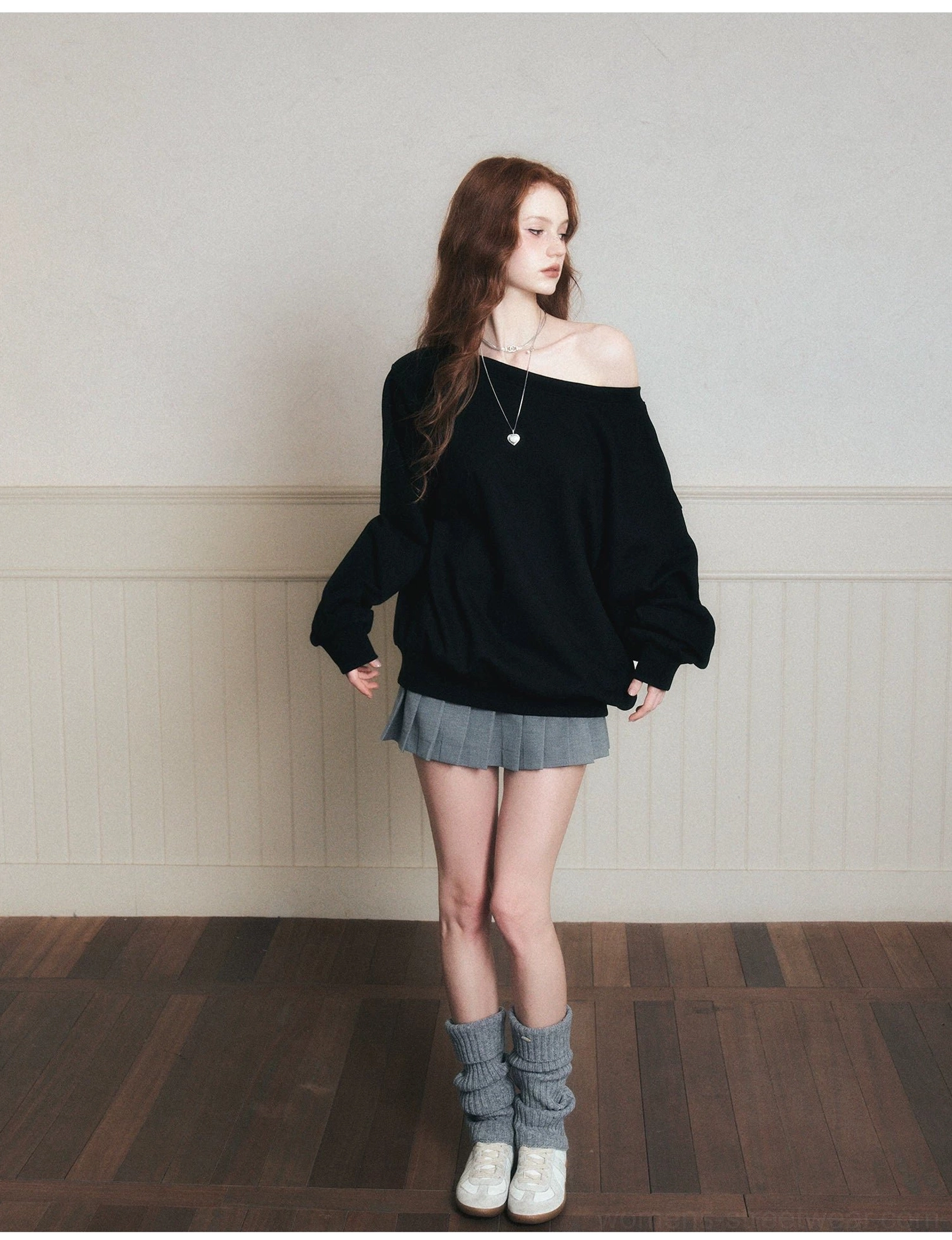Side view of black oversized off-shoulder sweatshirt with dropped shoulders and silver pendant necklace