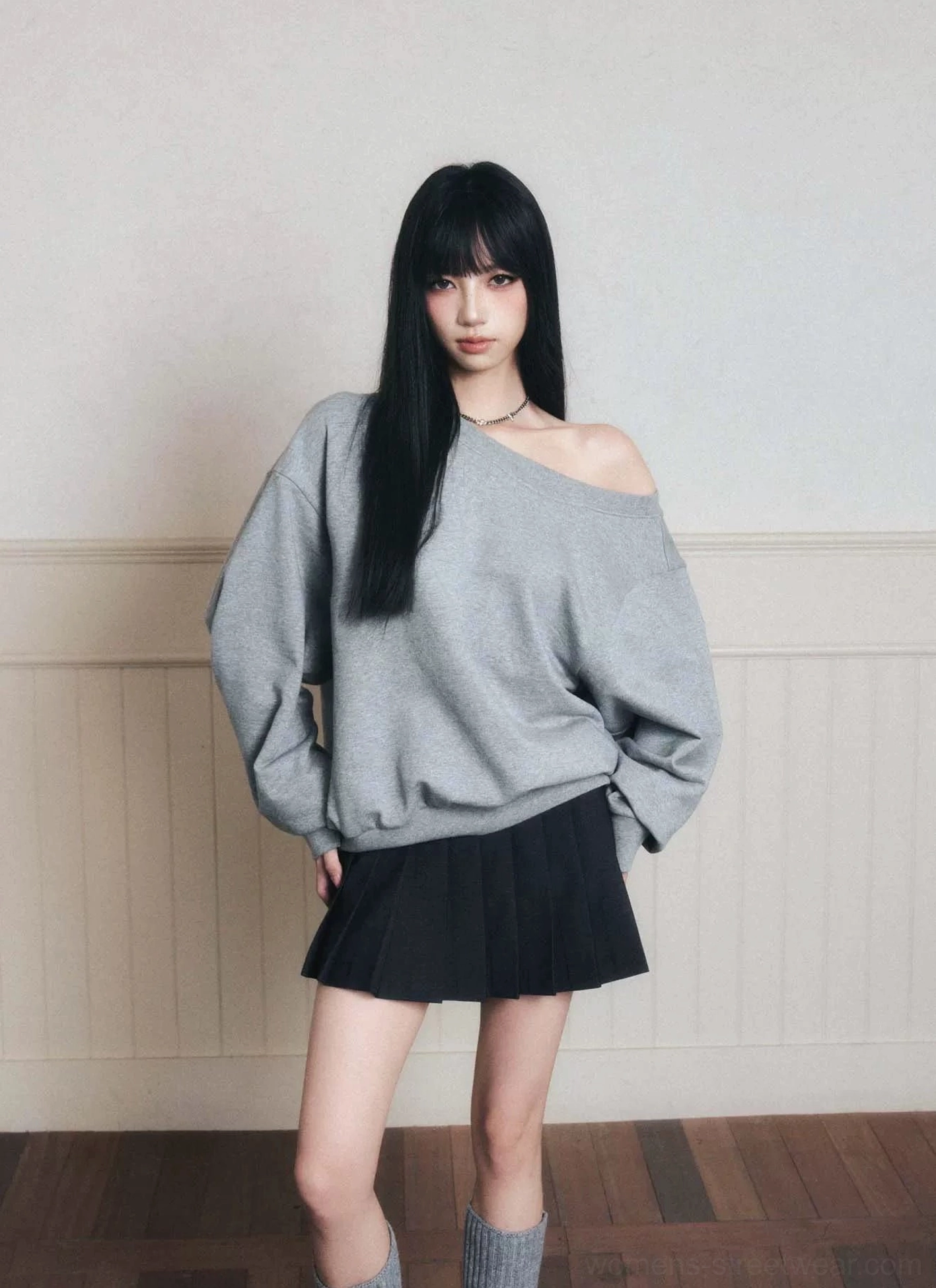 Back view of heather gray oversized off-shoulder sweatshirt with black pleated skirt