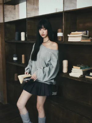 Gray oversized off-shoulder sweatshirt styled with black pleated mini skirt in campus fashion look