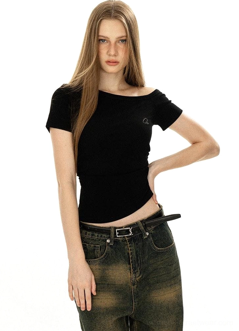 Off-shoulder minimalist tee worn layered under structured outerwear Gorpcore utility belt styling streetwear aesthetic