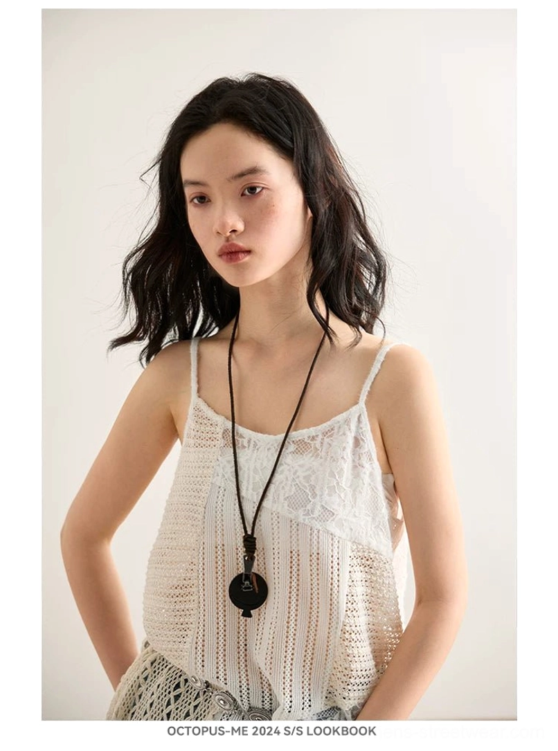 Off-white asymmetric crochet lace cami top with spaghetti straps styled with a long round pendant necklace in a minimal streetwear look