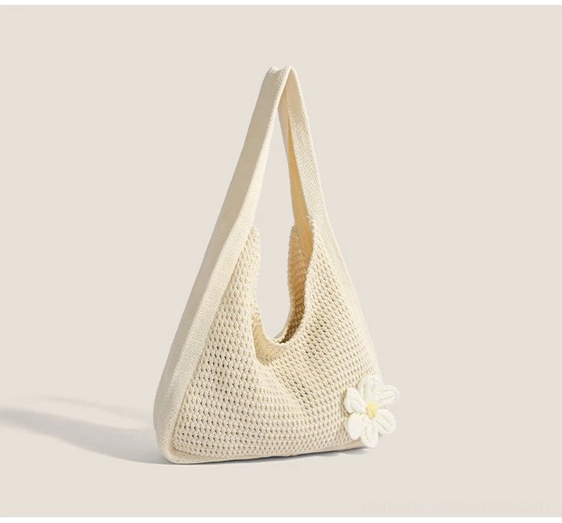 Off white crocheted hobo bag shown from the side with soft slouchy shape and wide fabric shoulder strap