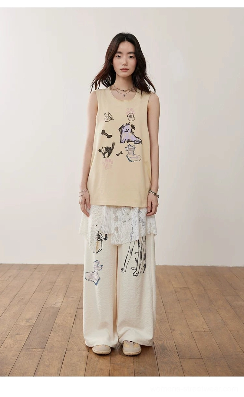 Off-white asymmetric crochet lace cami top layered over a cartoon print tank with illustrated wide-leg pants for playful Y2K streetwear