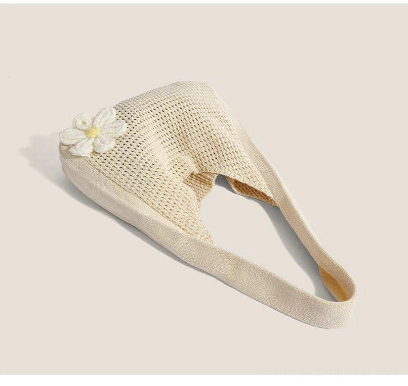 Flat lay view of an off white daisy crochet hobo bag showing woven texture, open top, and wide strap