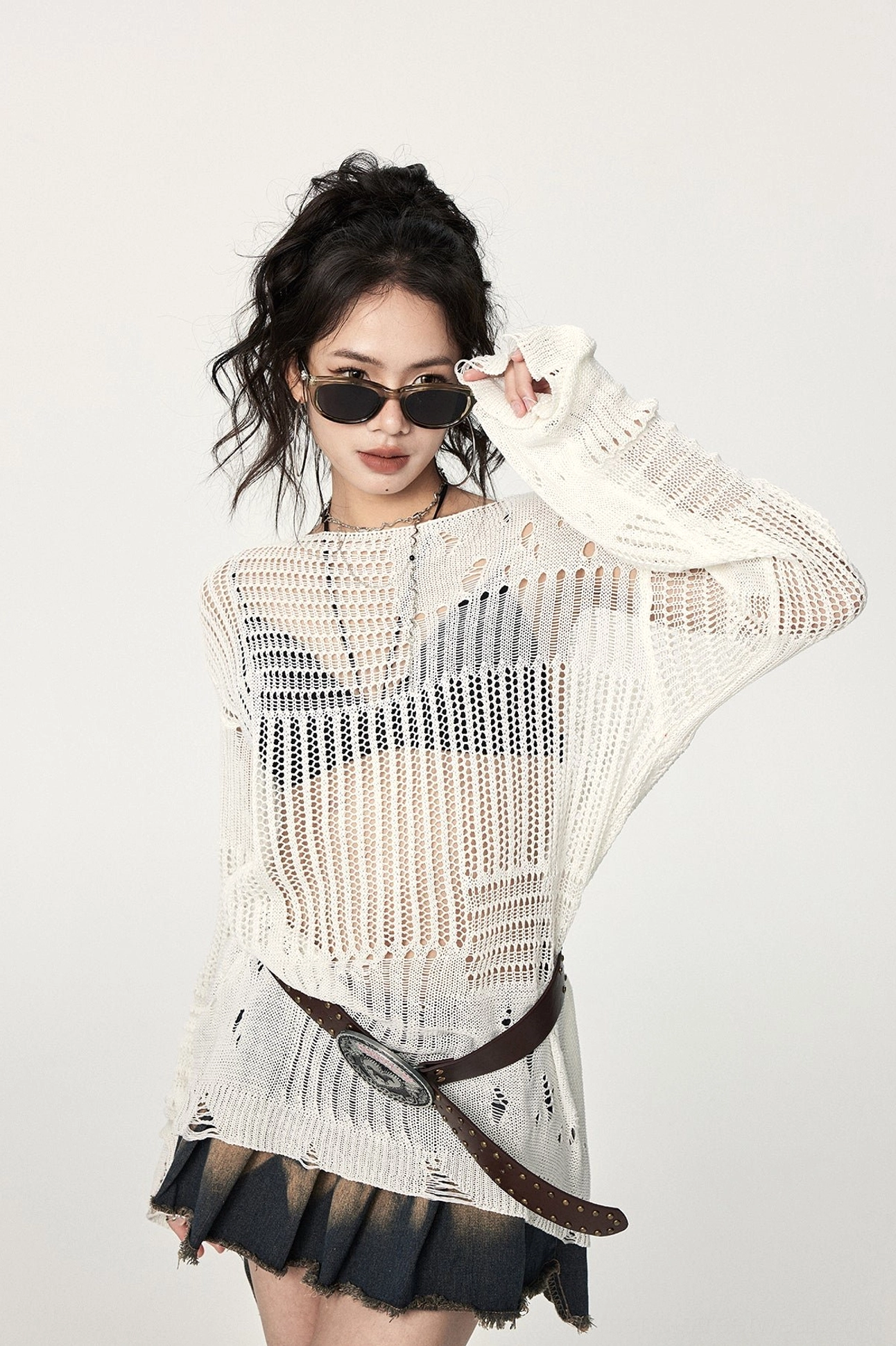 Off-white distressed crochet long-sleeve sweater showing open knit texture, ripped sleeve accents, relaxed fit, and layered fashion styling