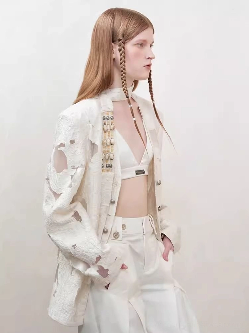 Side three-quarter view of off-white distressed cutout blazer with cropped bralette and high-waisted trousers