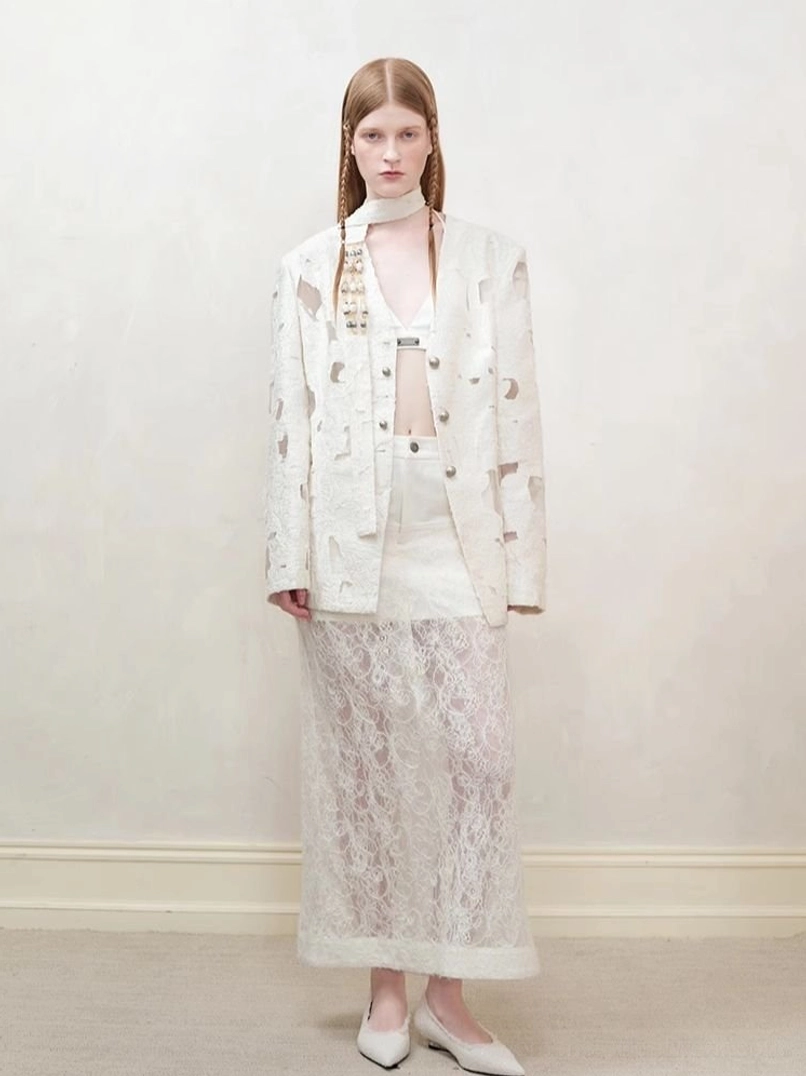 Women’s off-white distressed cutout blazer styled with floral lace midi skirt in a neutral studio setting